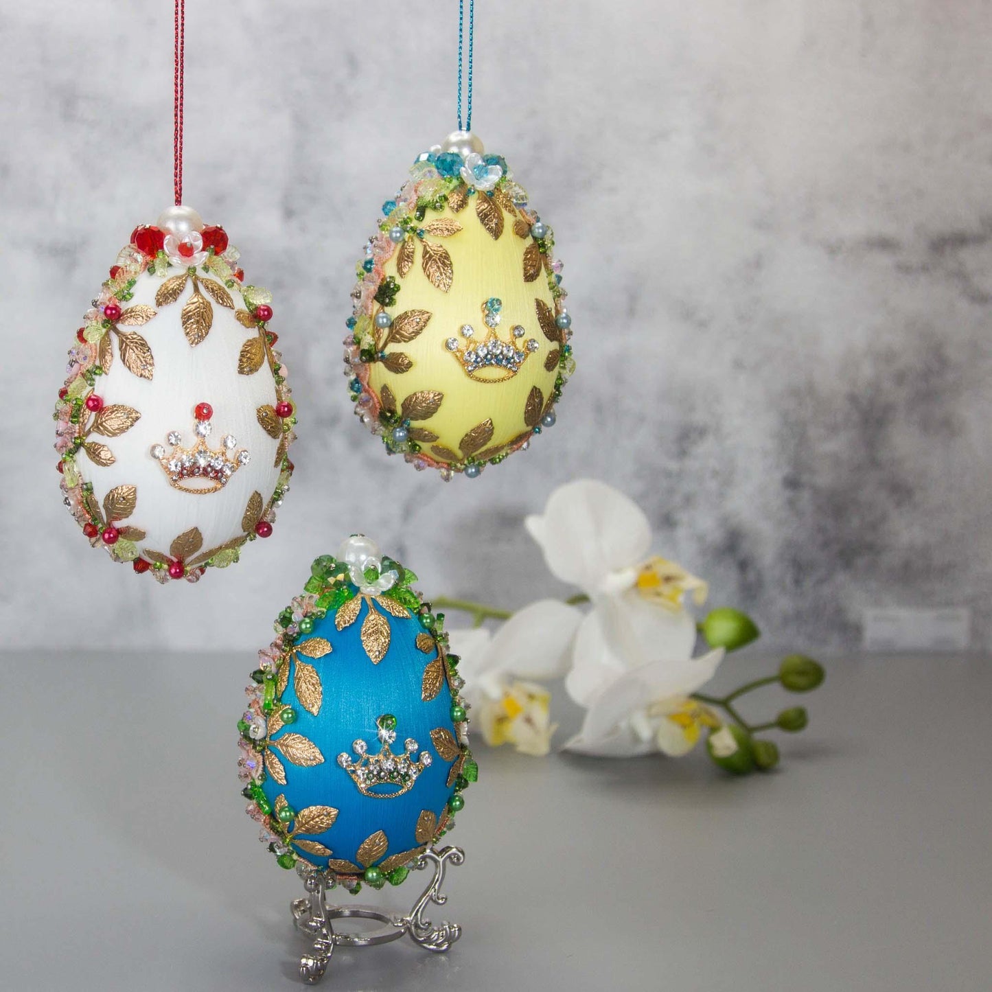 Collection of Handmade Vintage inspired Satin Easter Egg Ornaments embellished with gold crowns, flower trim, and beads.