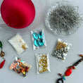 Load image into Gallery viewer, Assorted jewelry-making supplies including beads, pins, and a red ball on a gray surface. (Dark Red).