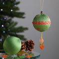 Load image into Gallery viewer, Green ornament kit with red maple leaf trim in front of a Christmas tree. (Olive)