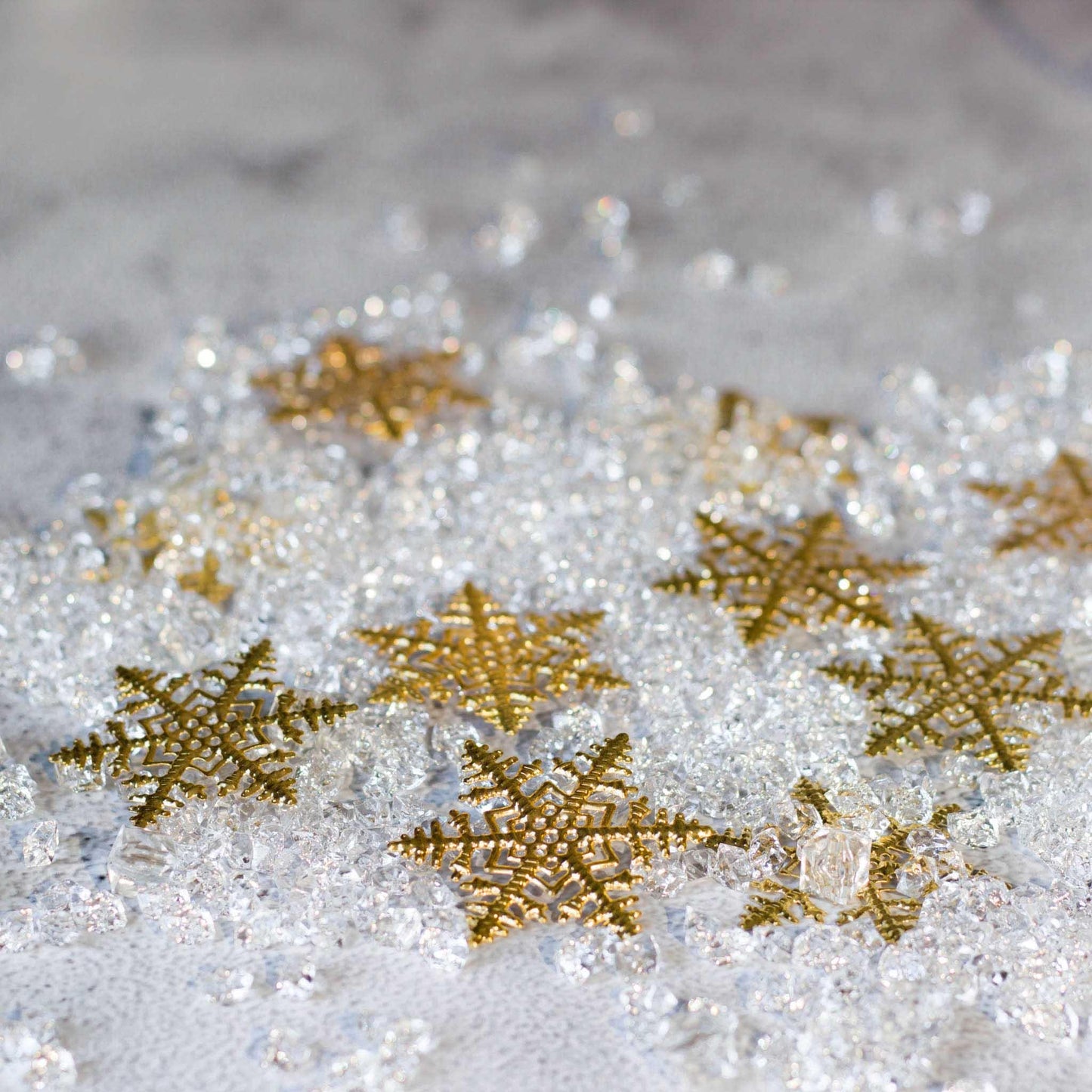 Gold metal alloy snowflake stamping on a background of icy crystals, sparling.