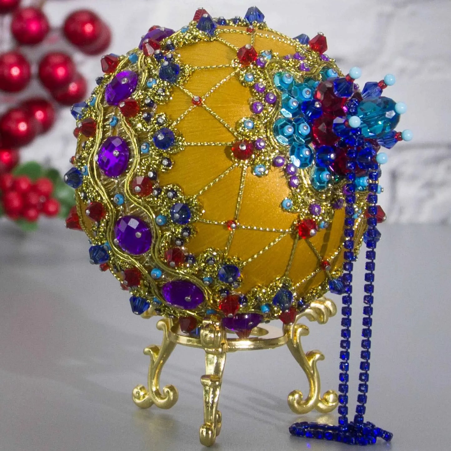 Close-up Detail of Scheherazade Handmade Satin Ornament -Festive mustard-colored ball with purple rhinestones, sparkling gold trim, sequins, indigo rhinestone chain, and metallic cord. (Gold)