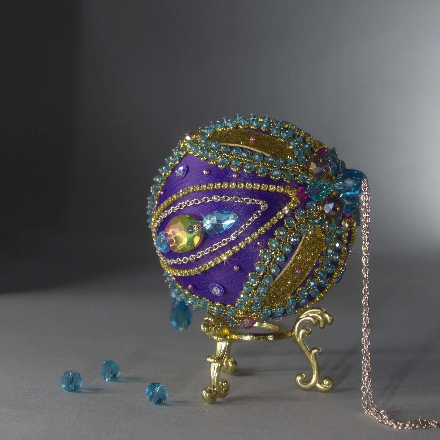 Christmas Beaded Ornament Kit Ball embellished with glass rhinestones, gold braided trim, and crystal beads. Top detail. (Indigo).
