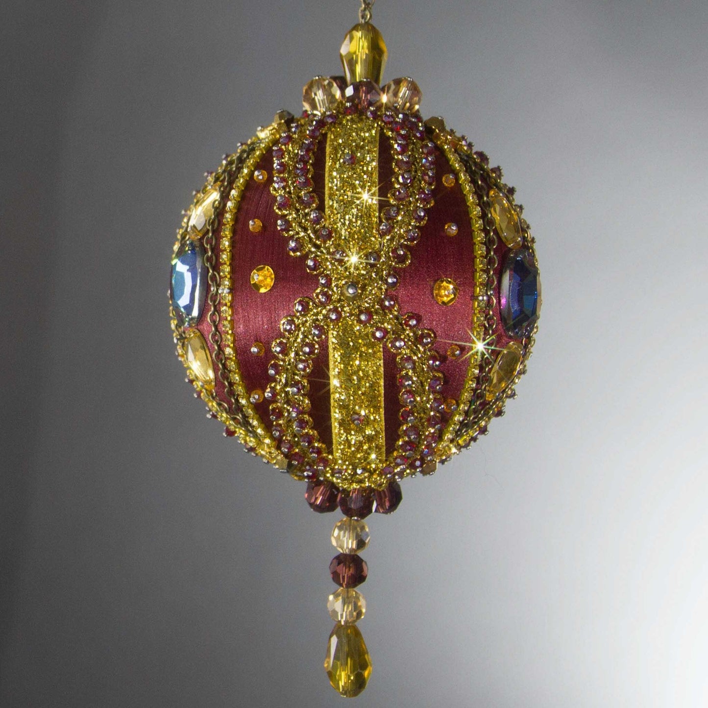 Christmas Beaded Ornament Kit Ball embellished with glass rhinestones, gold braided trim, and crystal beads. Front. (Maroon).