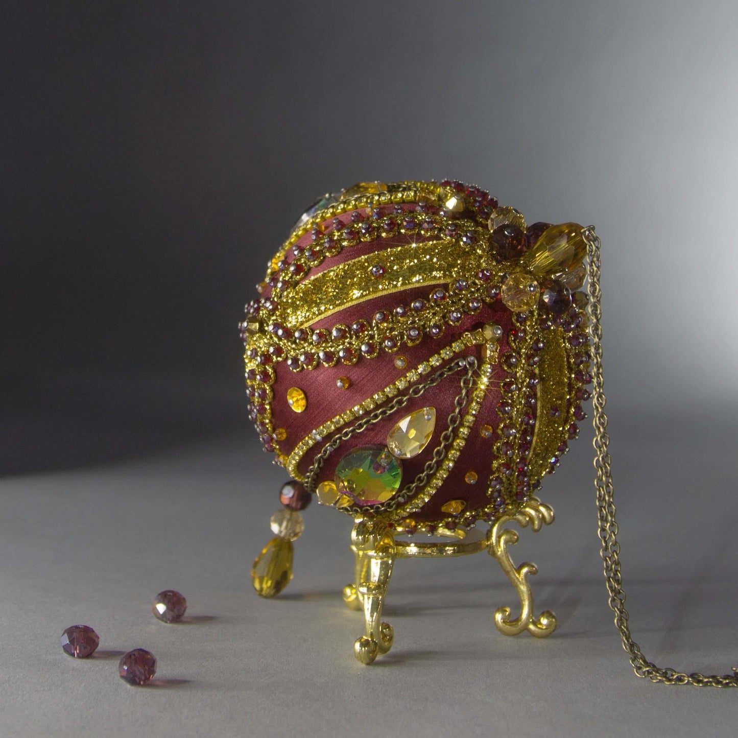 Christmas Beaded Ornament Kit Ball embellished with glass rhinestones, gold braided trim, and crystal beads. Top detail. (Maroon).