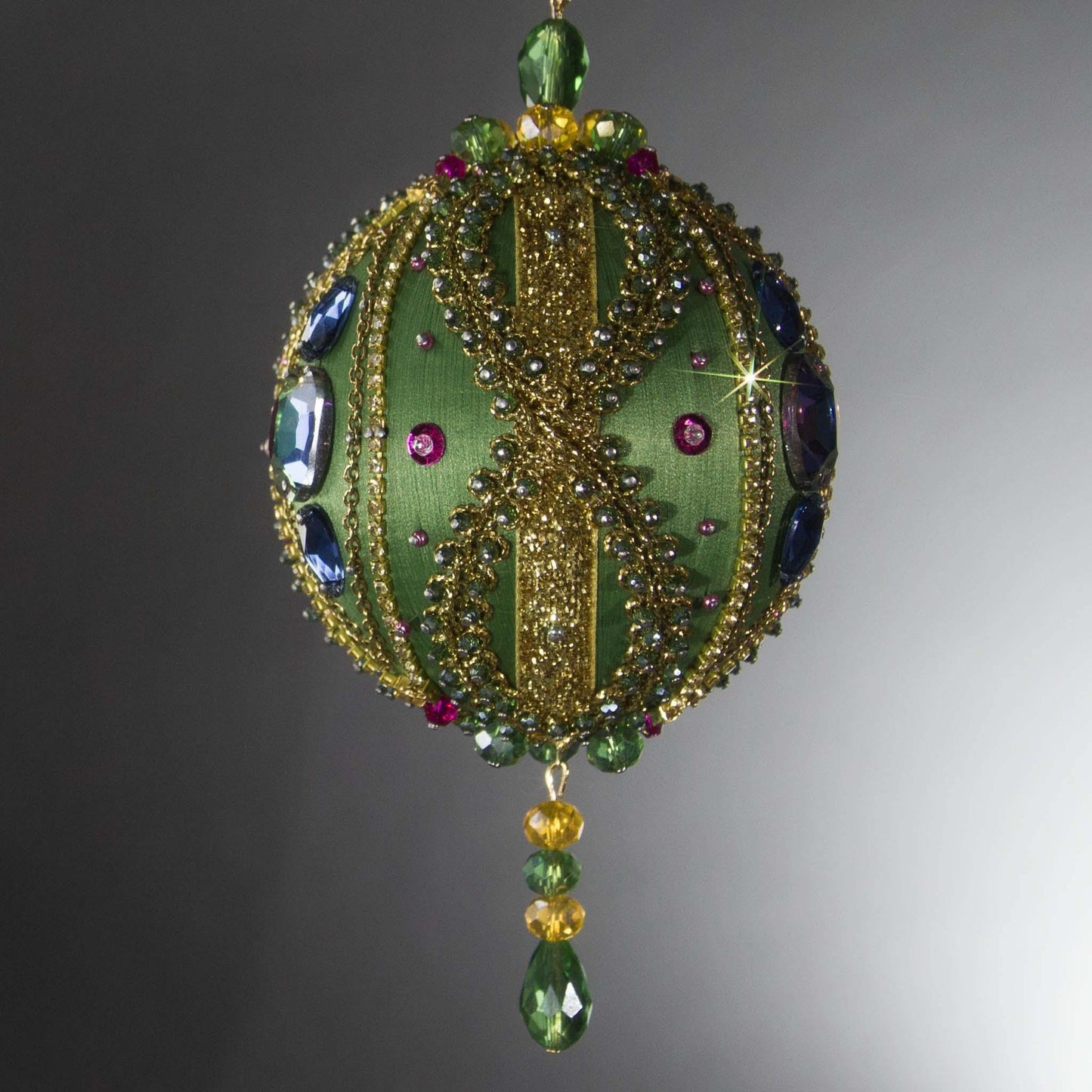 Christmas Beaded Ornament Ball embellished with large glass color-shifting rhinestones, gold braided trim, and crystal beads. Side view. (Olive).