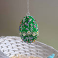 Load image into Gallery viewer, Decorative embroidered egg with floral patterns on a chain, placed on a woven surface. (Green)
