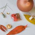 Load image into Gallery viewer, Push Pin Ornament includes these materials: assorted maple leaf charms, leaf ribbon, beads, and gold thread, on a light surface. (RosyBrown)