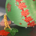 Load image into Gallery viewer, A close-up of a Handmade Push Pin Ornament in green featuring a rust colored maple ribbon trim pinned to a satin foam core with dressmaker pins, and some acrylic maple leaf charms. (Olive)