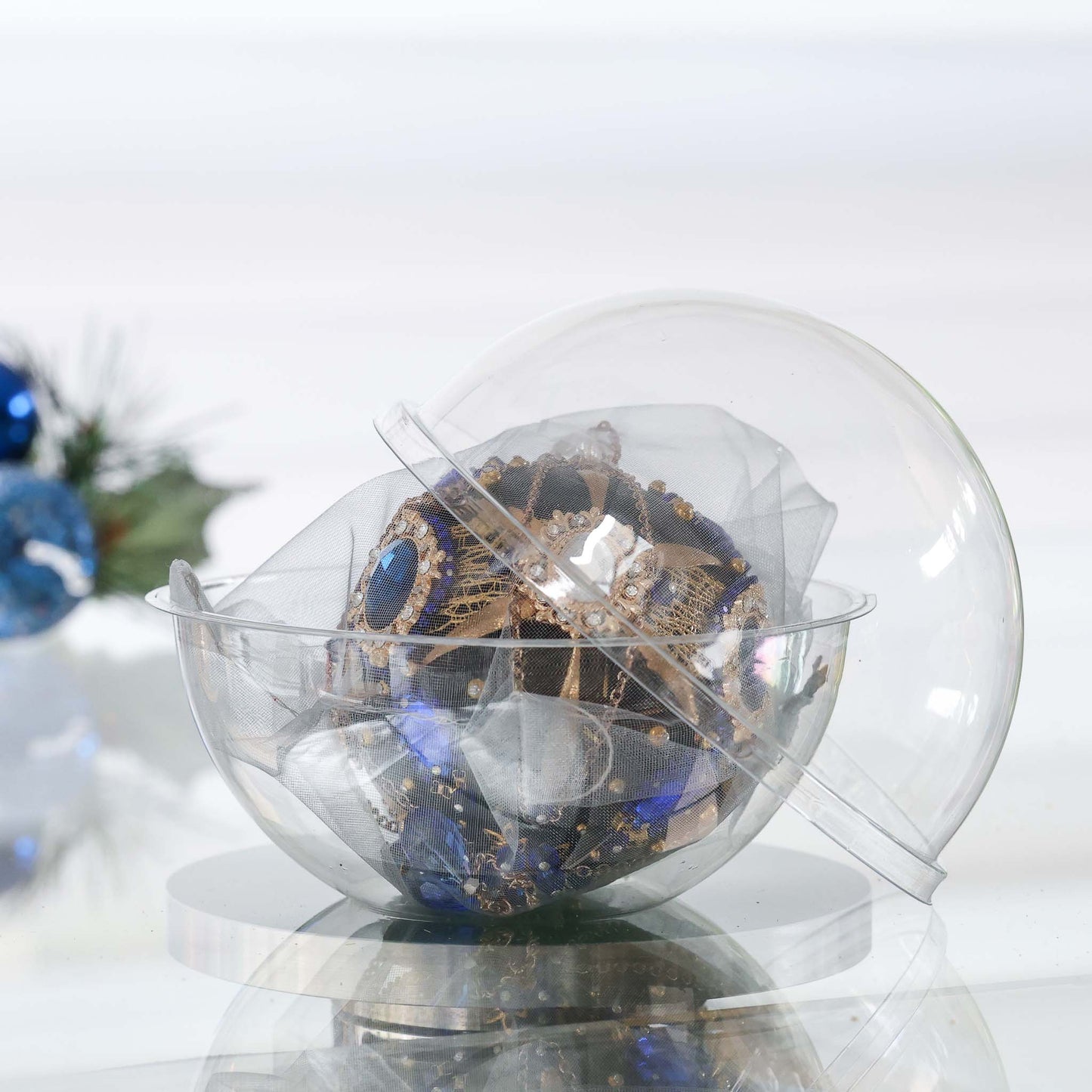 Handmade mid century style black satin push pin ornament featuring large cameos, blue rhinestones, and gold beads in a clear storage container with a Christmas branch in the background by Whim5seasons. (Black)
