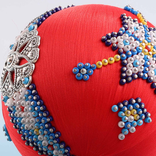 A close-up detail of a handmade push pin ornament showcasing indigenous style beadwork applied to a satin core with dressmaker pins by Whim5seasons.