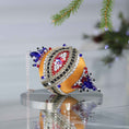 Load image into Gallery viewer, Handmade sequin & beaded push pin ornament featuring an eye design on a reflective surface with light gray background and holiday greenery by Whim5seasons.