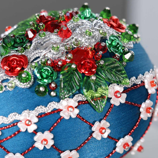 A close-up detail of a handmade Easter egg push pin ornament featuring dark blue color with red rose embellishments and green acrylic leaf charms by Whim5seasons. (Dark Slate Blue)