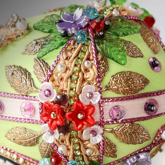 A close-up detail of a push pin Easter Egg showing small acrylic flowers pinned to a green satin foam core by Whim5seasons.