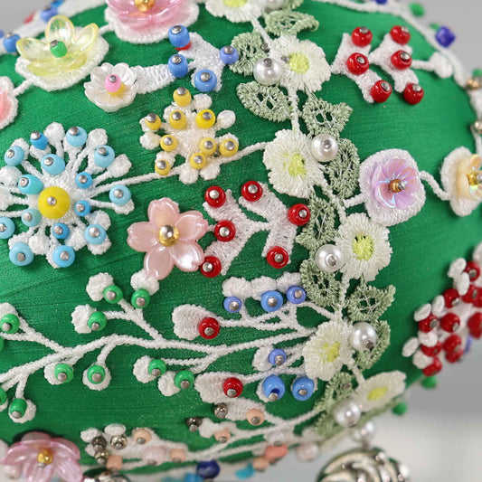 A close-up detail of a green Easter egg push pin ornament showing small beads and pearls pinned with dressmaker pins to the satin core.