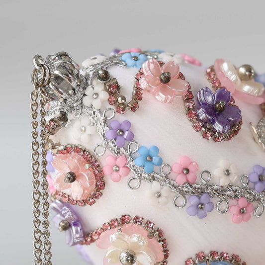 A close-up detail of a handmade Easter egg push pin ornament featuring small silver crown and pastel acrylic flower charms by Whim5seasons.