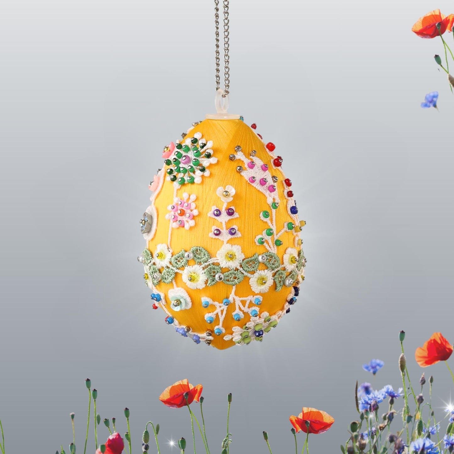 Decorative satin egg with floral patterns hanging on a chain on a light gray background by Whim5seasons.