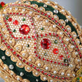 Load image into Gallery viewer, Close up of a handmade gold Christmas beaded ornament featuring red acrylic rhinestones, gold trim, and hundreds of small pearl beads, pinned to a satin core with dressmaker pins.