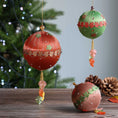 Load image into Gallery viewer, Collection of three completed handmade push pin ornaments in green, brown, and rust color in front of a Christmas tree and a wooden tables with some pinecones.