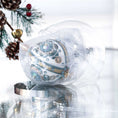 Load image into Gallery viewer, Handmade retro Christmas beaded ornament with intricate design on a reflective surface in a clear storage box with an evergreen branch in the background.