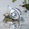 Load image into Gallery viewer, Handmade Christmas satin push pin ornament in white with blue and silver sequined holiday wreath, snowman bead, and a large Tibetan style bead with green branches on a gray background.