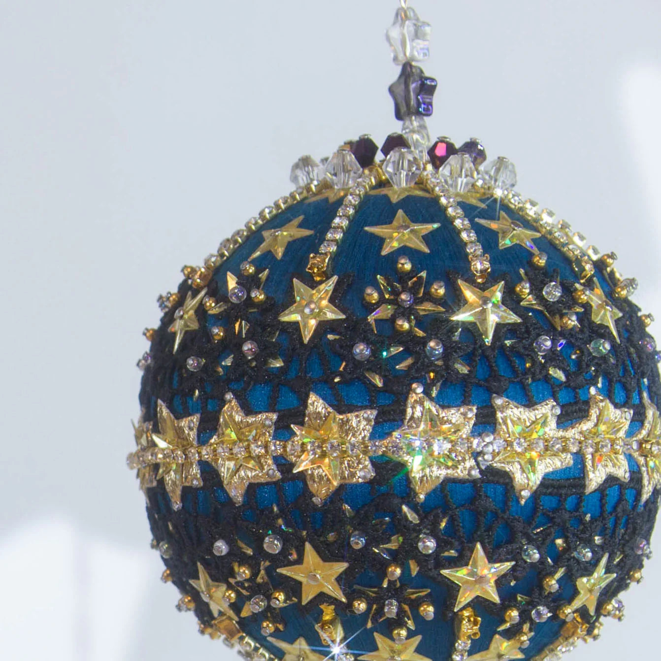 A close-up of a handmade New Year Star Ornament from Whim5seasons. It features sparkling rhinestones, and gold accents set on a rich fark blue satin ball. (Dark Slate Blue)