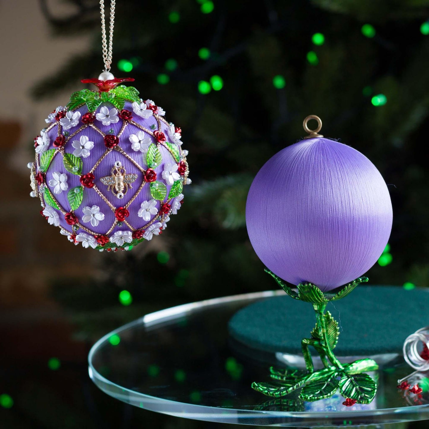 Decorative Christmas ornament with intricate design on a table in front of a blurred Christmas tree. (Medium Purple).