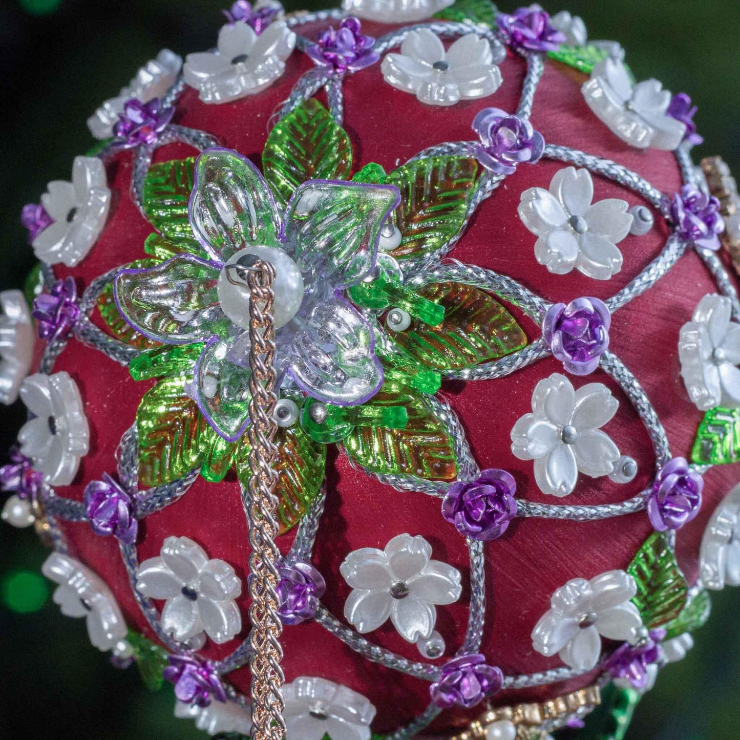 Decorative red handmade ornament with flowers, beads on a blurred green background DIY. (Dark Red).