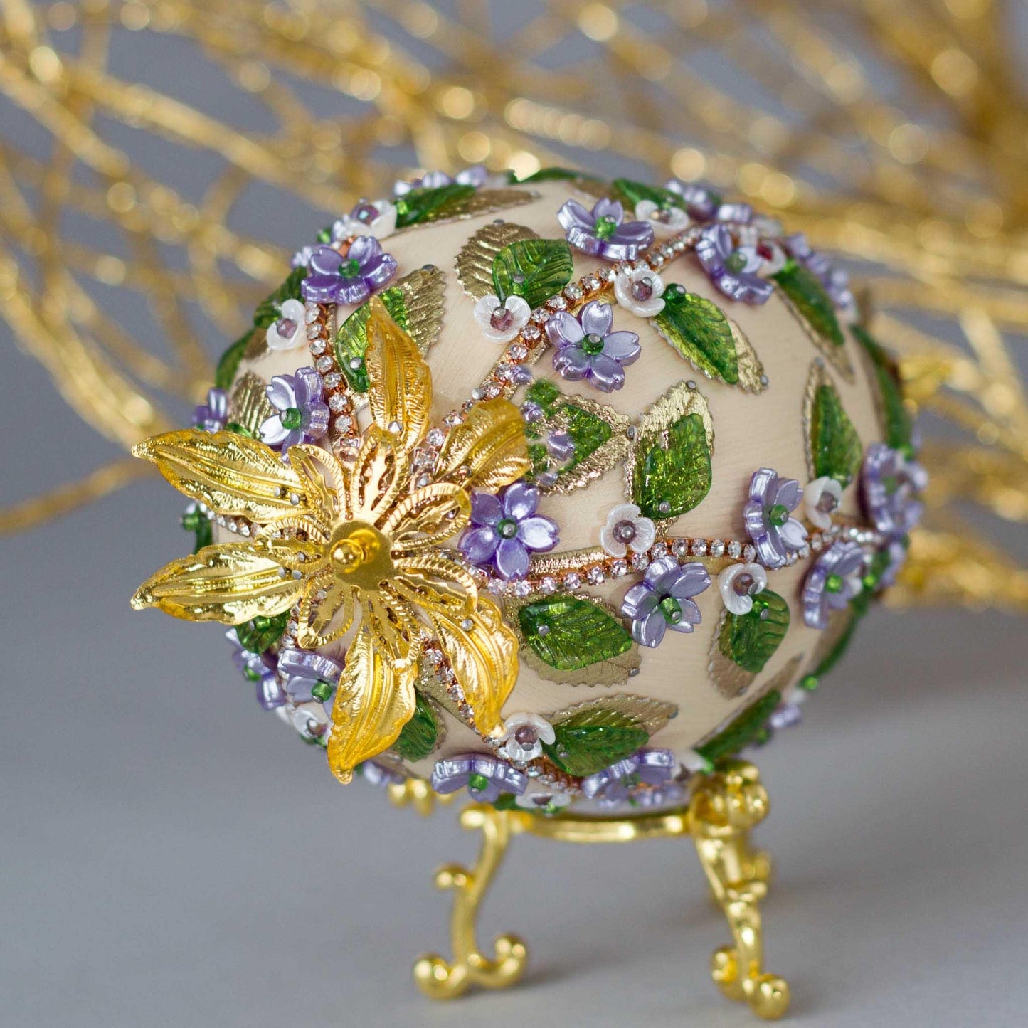 Vintage inspired charming Easter Egg Beaded Ornament embellished with flowers, leaves, gold floral trim, and crystal beads. Top detail. (Old Lace).