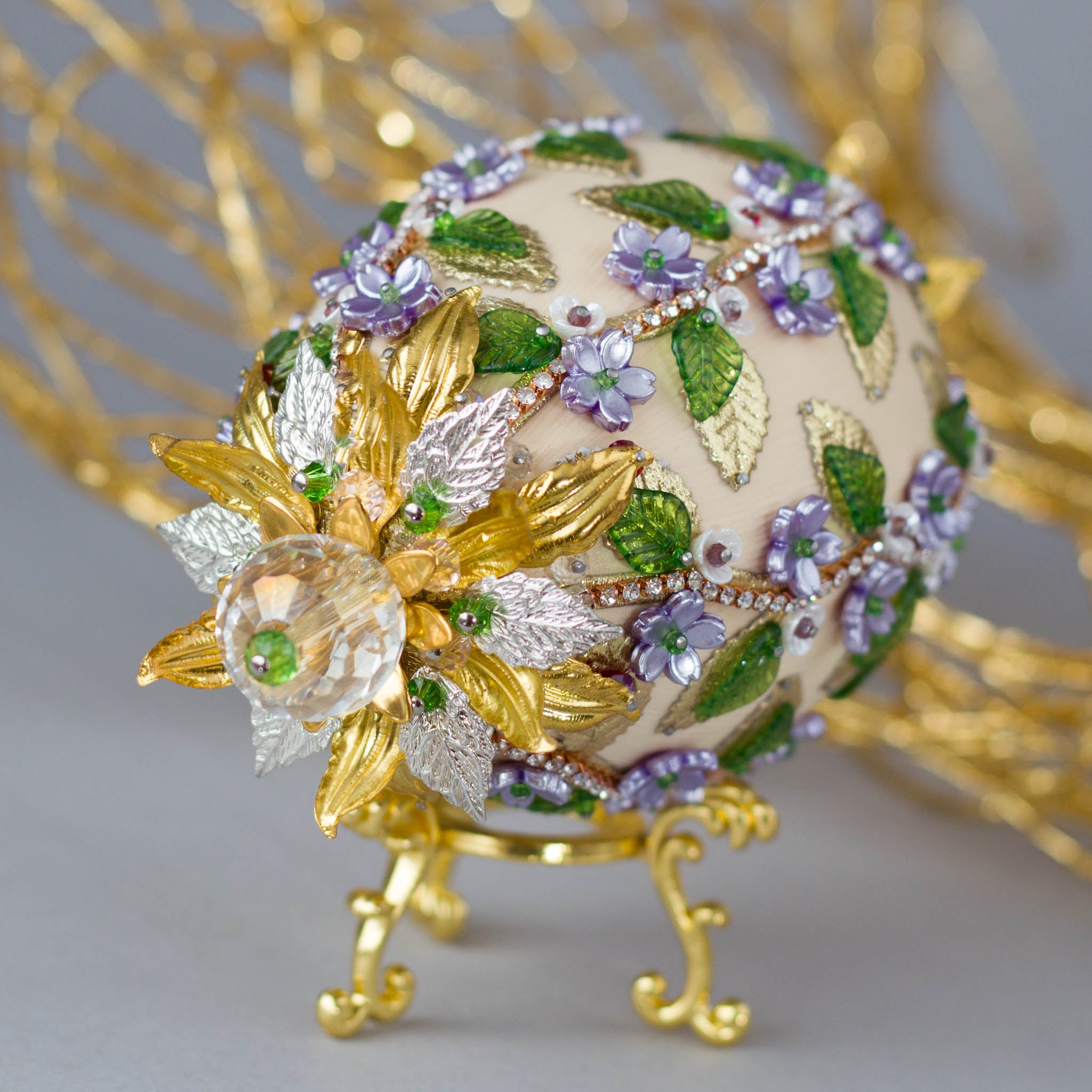Vintage inspired charming Easter Egg Beaded Ornament embellished with flowers, leaves, gold floral trim, and crystal beads. Top detail. (Old Lace).