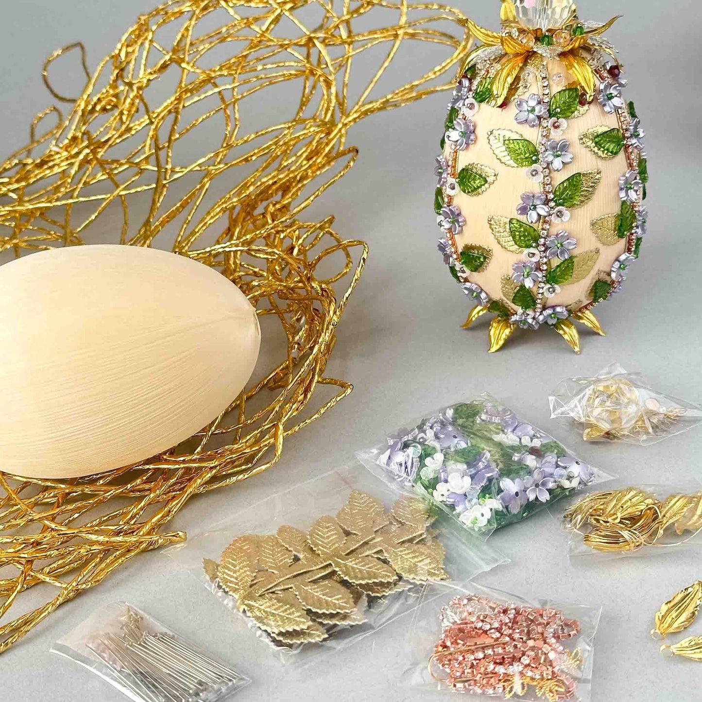 Materials to make Easter Egg Push Pin Ornament by pinning glass rhinestones chains, gold, and crystal beads to a satin ball. (Old Lace).