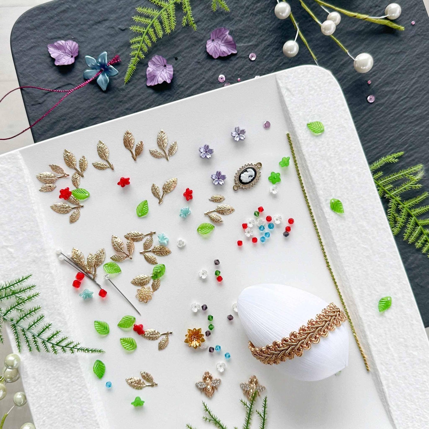 Materials to make Easter Egg Beaded Ornament by pinning glass rhinestones chains, gold, and crystal beads to a satin ball. (White).