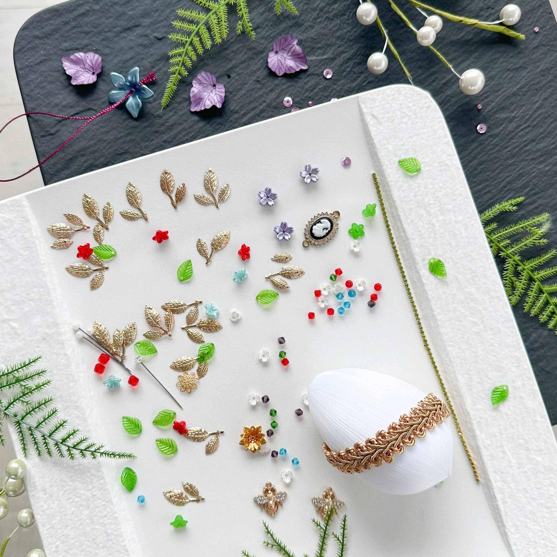 Materials to make Easter Egg Beaded Ornament by pinning glass rhinestones chains, gold, and crystal beads to a satin ball. (White).