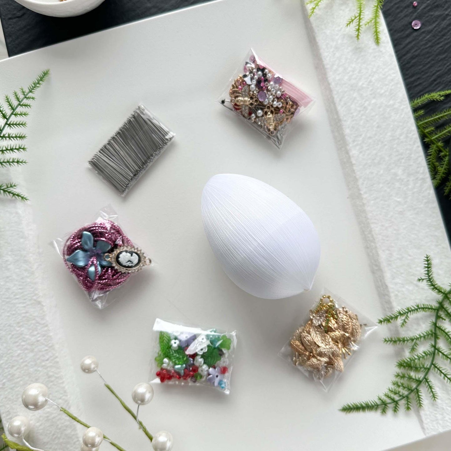 Materials to make Easter Egg Beaded Ornament Anna by pinning glass rhinestones chains, gold, and crystal beads to a satin ball. (White).