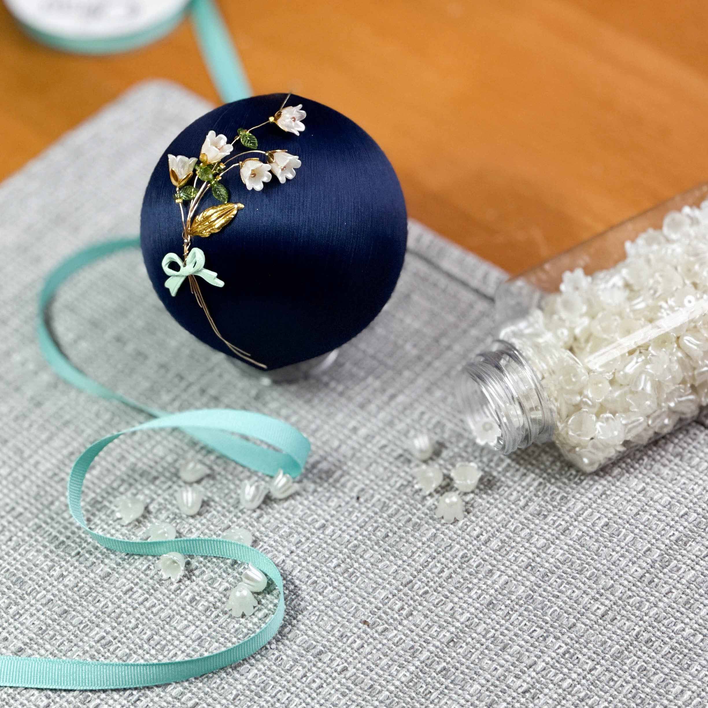 Large satin deep blue ornament with lilly-of-the-valley flowers.