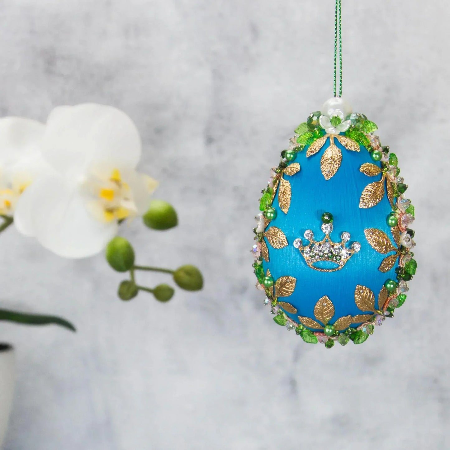 Golden Crown Easter Egg Beaded Ornament embellished with flowers, gold leaves, floral trim, and crystal beads. Front. (Sky Blue).