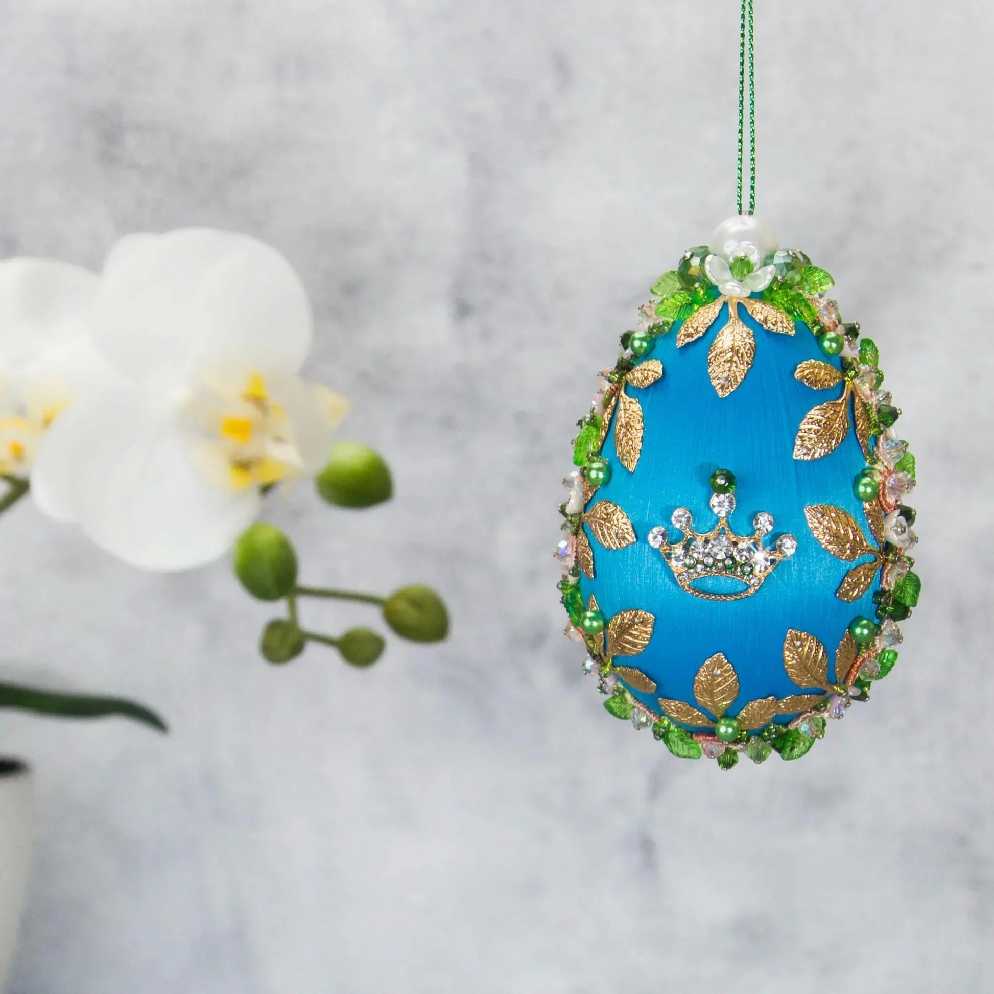Golden Crown Easter Egg Beaded Ornament embellished with flowers, gold leaves, floral trim, and crystal beads. Front. (Sky Blue).