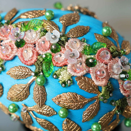 Golden Crown Easter Egg Beaded Ornament embellished with flowers, gold leaves, floral trim, and crystal beads. Top detail. (Sky Blue).