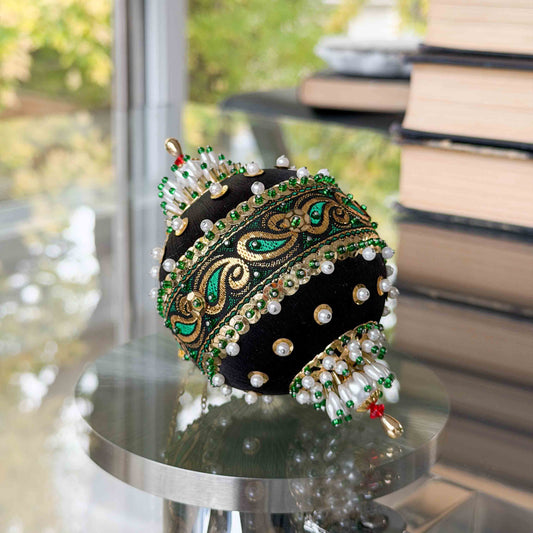 Decorative headpiece with green and gold accents on a reflective surface