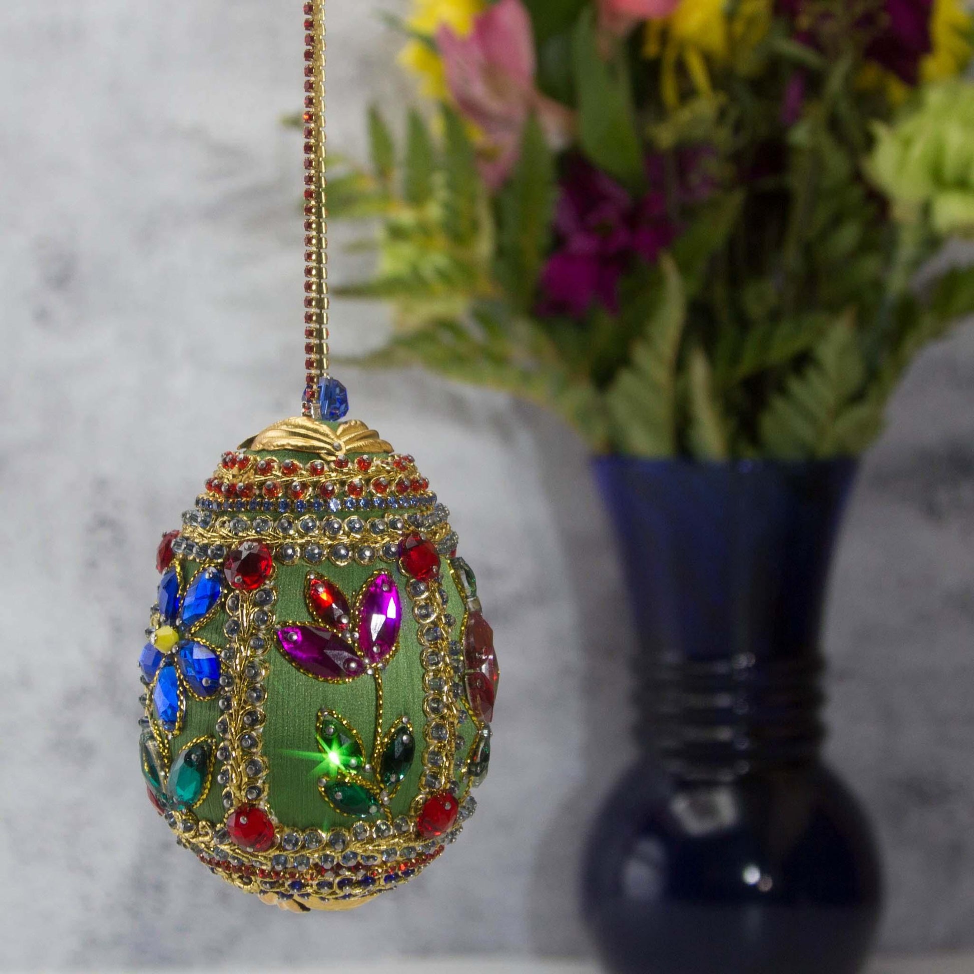 Handmade Easter Egg Beaded Ornament embellished with flowers, leaves, gold floral trim, and crystal beads. Side. (Olive).