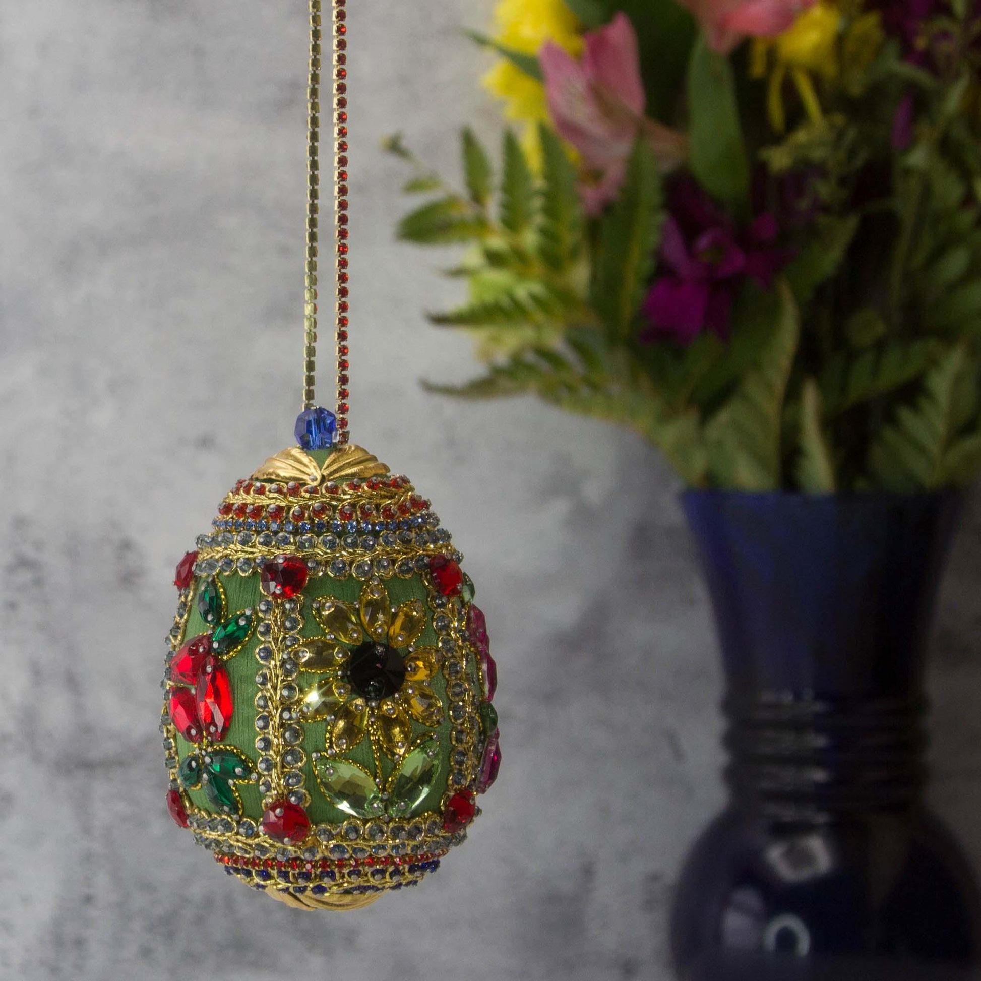 Handmade Easter Egg Beaded Ornament embellished with flowers, leaves, gold floral trim, and crystal beads. Side. (Olive).