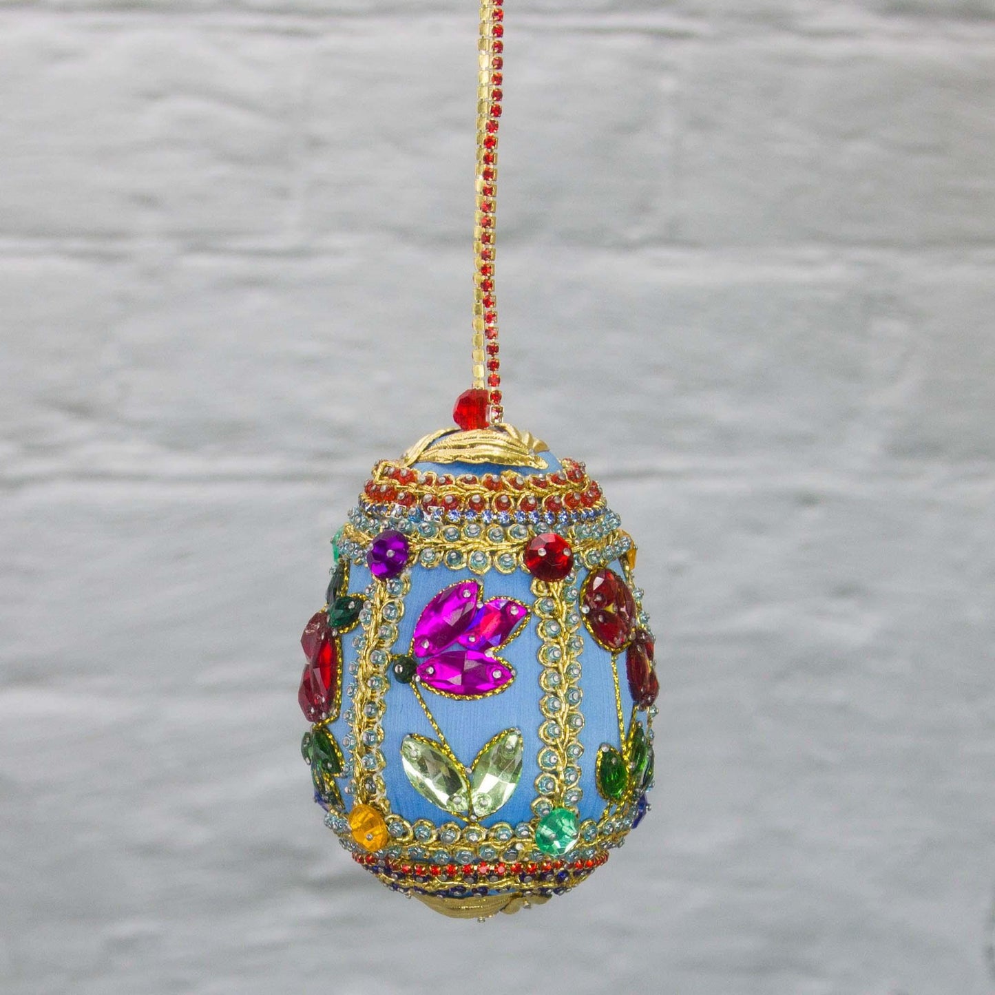 Handmade Easter Egg Beaded Ornament embellished with flowers, leaves, gold floral trim, and crystal beads. Side. (Sky Blue).