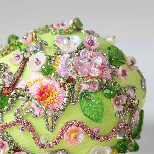 Close up of a handmade Easter Egg Push Pin Ornament embellished with tiny pink flowers and embroidered patches resembling Faberge style egg on a gray background by Whim5seasons.