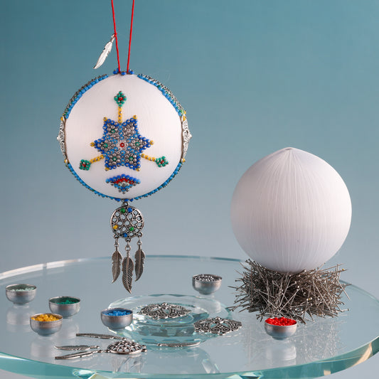 White 3" satin ball with a star design and feather charms on a clear stand against a light blue background. (White)