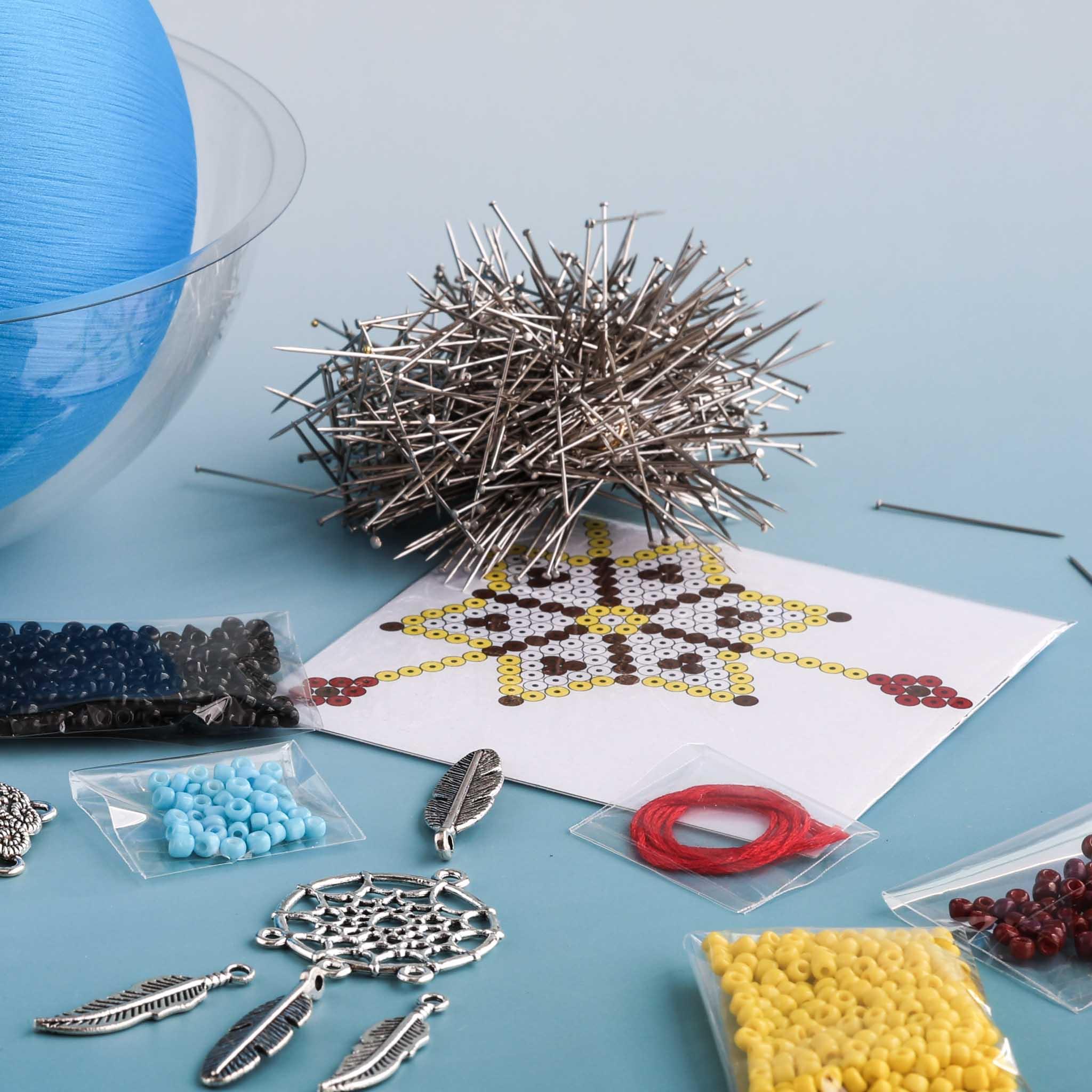 Crafting materials including beads, pins, and a partially completed star design on a blue surface. (Sky Blue)