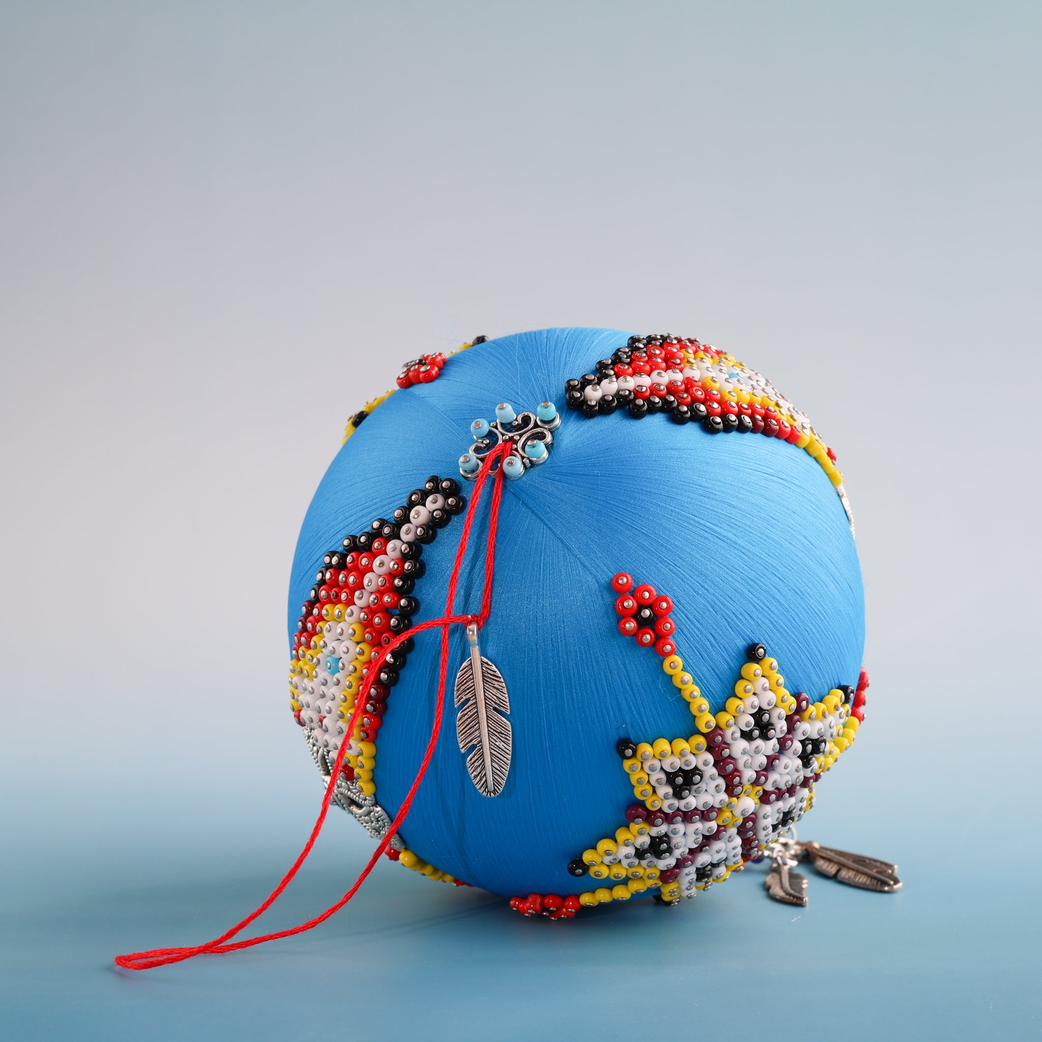 Decorative blue spherical object with bead patterns on a gray background.  (Sky Blue) 
