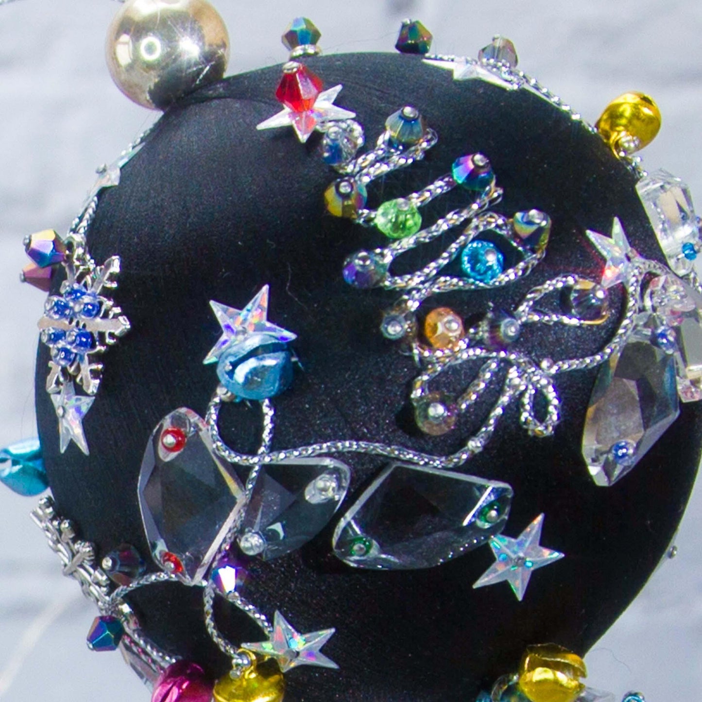 Close-up of a satin beaded ornament Jingle Bells, handmade black Christmas push pin decoration, featuring large glass beads, sparkling silver trim, sequins, and alloy snowflakes.