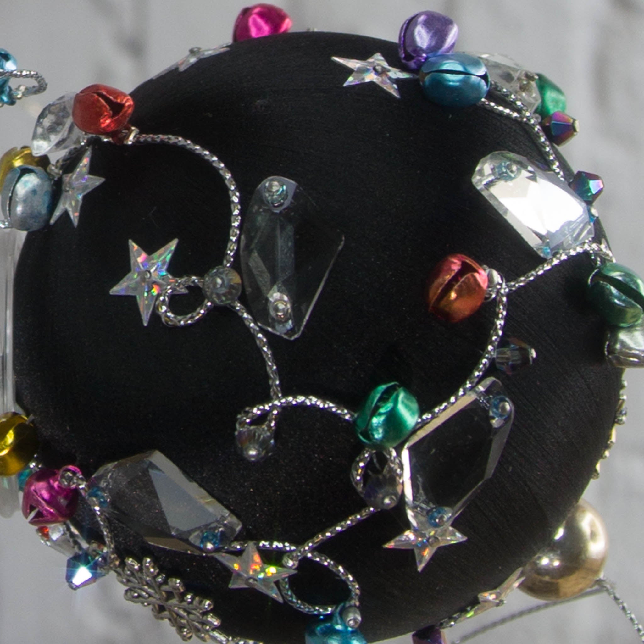 Close-up of a satin beaded ornament Jingle Bells, handmade black Christmas push pin decoration, featuring large glass beads, sparkling silver trim, sequins, and alloy snowflakes.