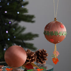 Decorative Christmas ornament with green maple leaf details on a gray background with pinecones. (RosyBrown)