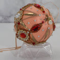 Load image into Gallery viewer, Close-up of Phoenix Christmas Beaded Handmade Satin Ornament, embellished with large gold cameos, rhinestones, gold alloy accents, and copper cobweb lace. (Coral)
