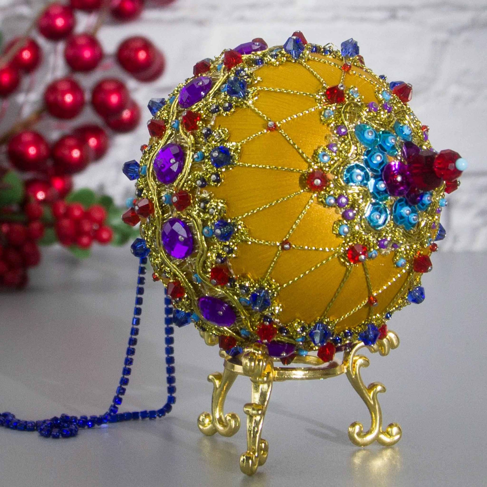 Close-up of the Bottom of Scheherazade Handmade Satin Ornament -Festive mustard-colored ball with red beads, rhinestones, gold trim, sequins, indigo rhinestone chain. (Gold) 